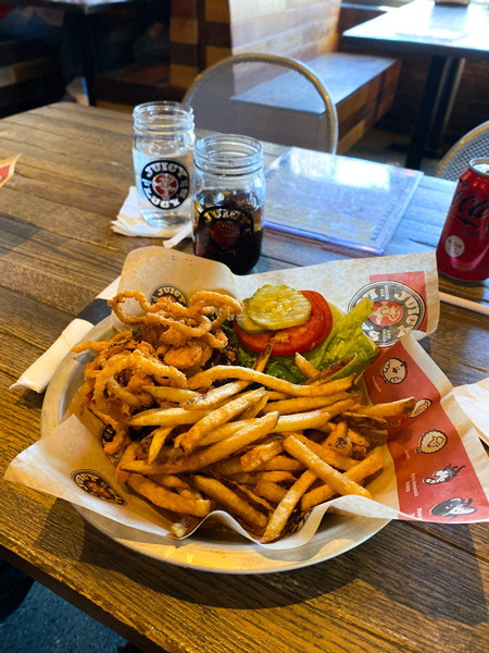 Juicy Lucy's Burger Asheville NC with picture of open-faced beef burger with fried onions, pickles, lettuce, and tomato with side of fries