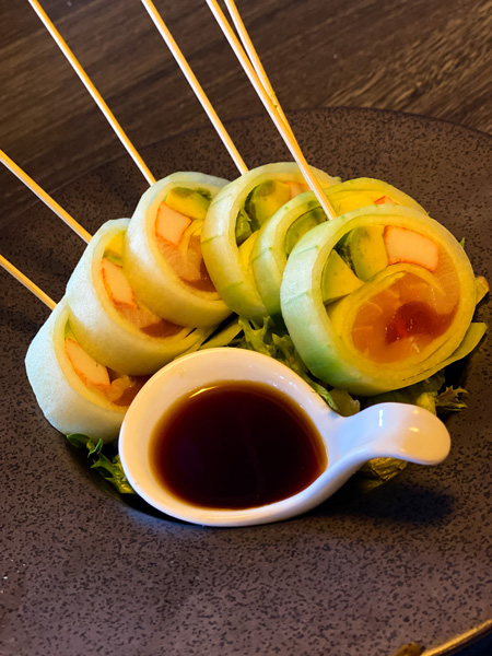 The Madness Asheville Burgers Sushi with sushi rolls on stick with spoon of soy sauce