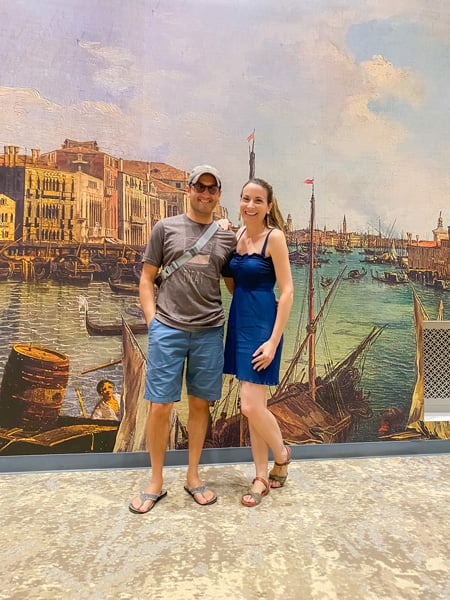 Christine and Tom, white brunette male and female in summer clothes, in front of painting of Venice at Biltmore Estate (special exhibit)
