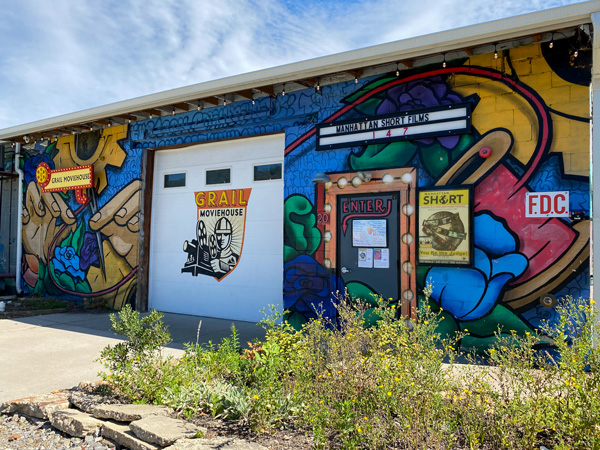 Grail Moviehouse Asheville NC with street art on building and white garage door with film strip logo