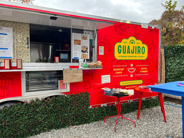 Guajiro Asheville River Arts District Food Truck facade with red truck with yellow and green logo lettering along with condiment table