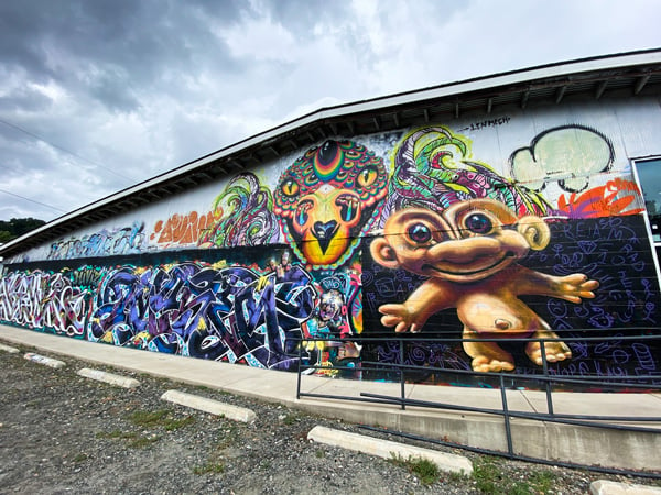 Jerry Cahill Troll in Asheville Art District with colorful urban art on warehouse