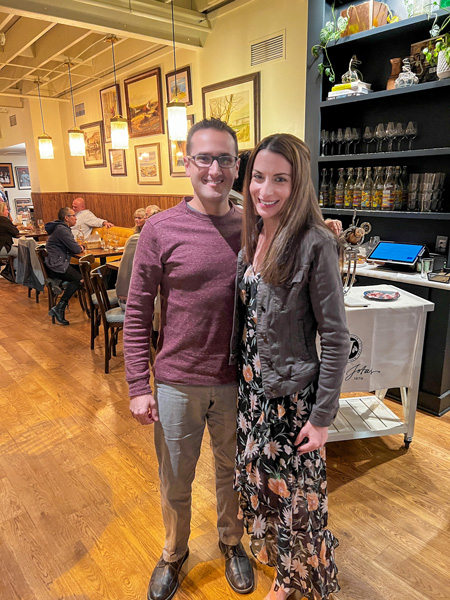 Christine and Tom, a white brunette male and female dressed up and posing for a photo, at La Bodega by Curate Asheville NC