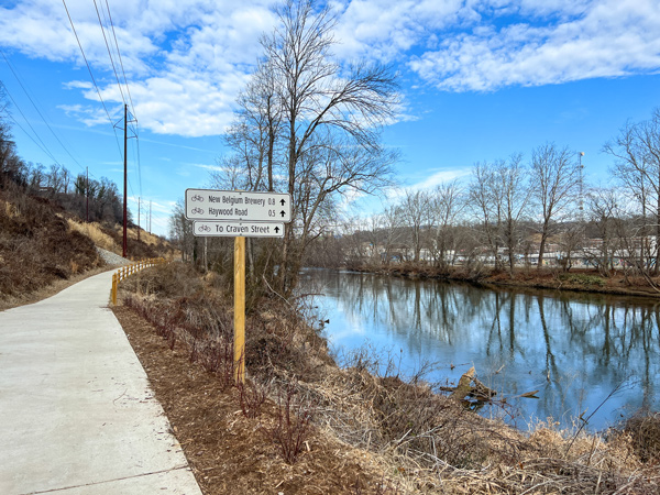 New Belgium Brewing access from the French Broad River Greenway which is a concrete paved trail along the French Broad River with a sign in the photo telling you the brewery is coming up