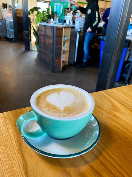 Summit Coffee River Arts District In Asheville NC with latte in turquoise cup on table with heart in foam