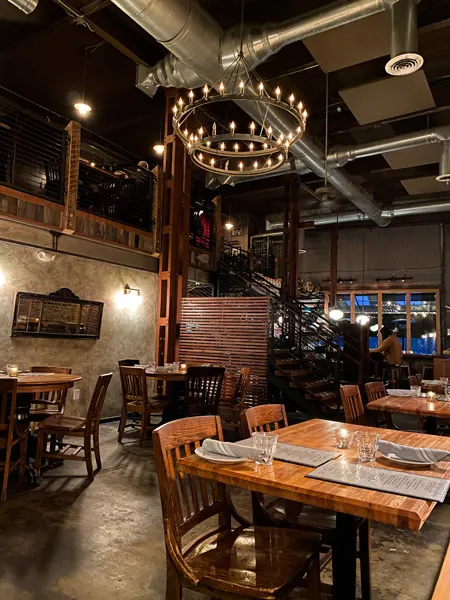 The Bull and Beggar River Arts District Asheville fine dining with chandelier, tables, and brick and stone wall