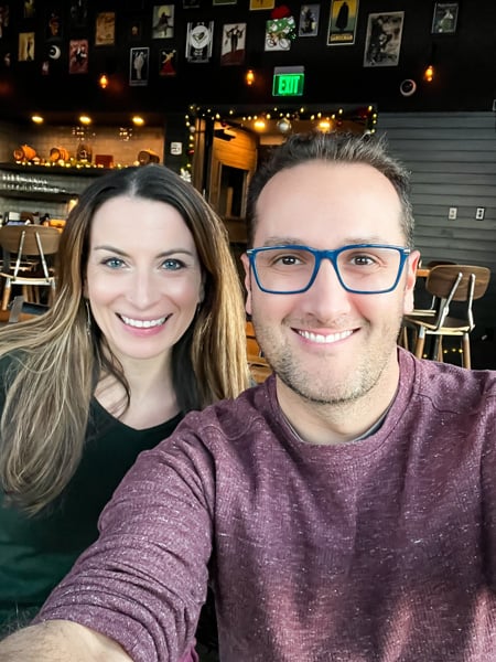Christine and Tom, a white brunette male and female in winter sweaters, taking a selfie at The Montford Rooftop Bar in Asheville, NC