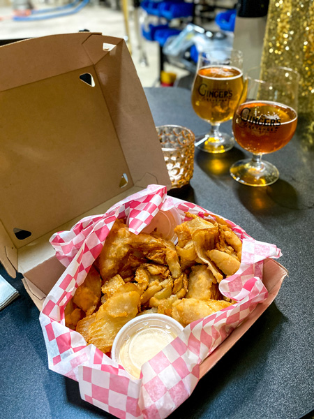 The Smokin Onion Ginger's Revenge RAD Asheville with fried onion rings and two glasses on ginger beer