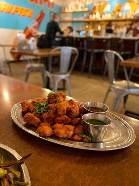 Silver plate filled with Indian food like chicken pakoras and green and brown dipping sauce at Chai Pani in Asheville, NC