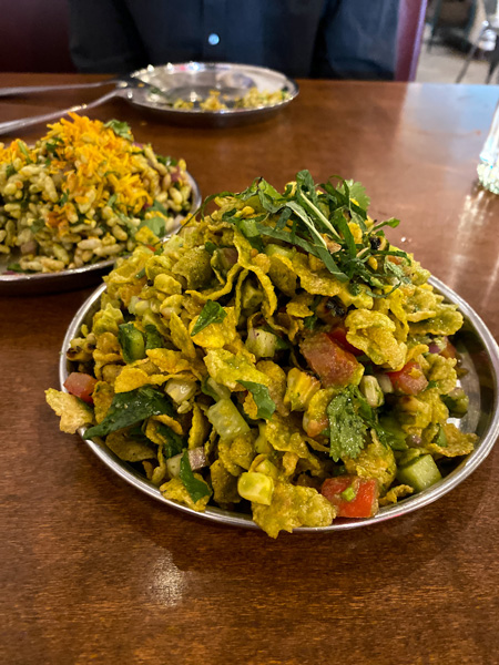 Corn Bhel from Chai Pani Asheville food Asheville with corn chips, cilantro and tomatoes on silver plate