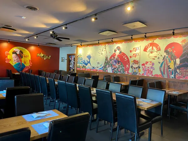 Itto Ramen Bar Tapas Asian Restaurant Asheville with brown tables, black chairs, and Japanese-themed murals on walls