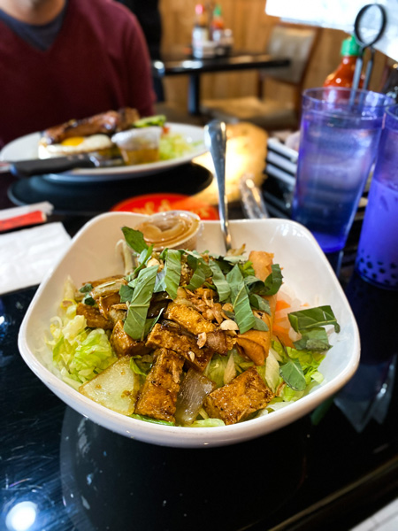 Wild Ginger Noodle Bar Restaurant Asheville NC with white bowl filled with rice vermicelli, tofu, lettuce, and veggies