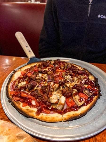 828 Family Pizzeria in Asheville NC with gluten-free pizza crust topped with BBQ sauce, bacon, chicken, red onion, and tomato