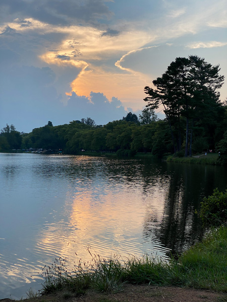 Beaver Lake North Asheville NC at sunset with blue and pink clouded sky at sunset over blue and darkening lake surrounded by trees