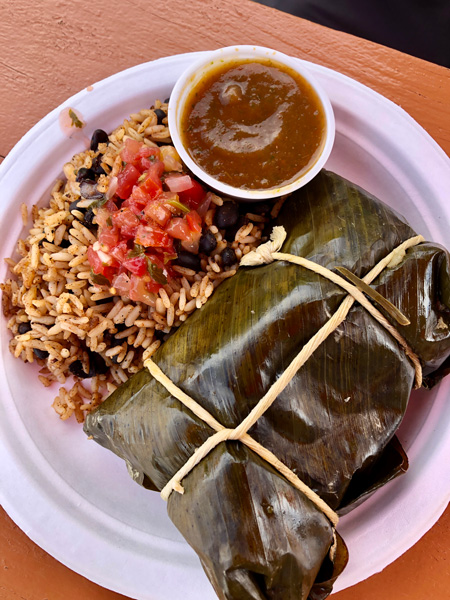 Cecilia's Kitchen North Asheville NC with white paper plate filled with large green leaf hiding meat tied with string next to rice and dipping sauce