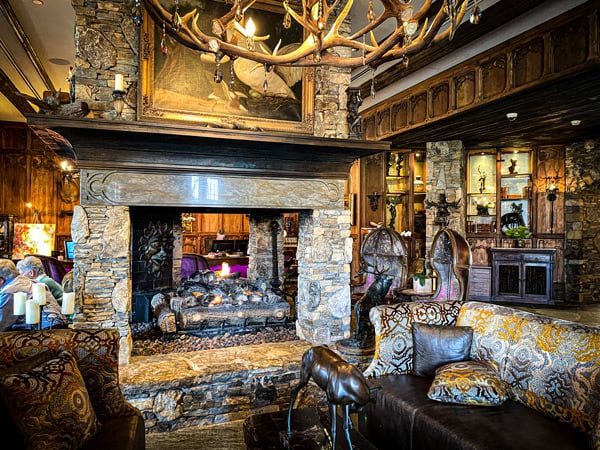 Grand Bohemian Hotel Asheville Lobby with large four-side stone fireplace surrounded by boutique chairs and couches with antler chandelier
