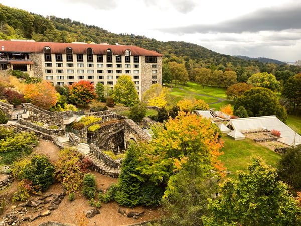 Omni Grove Park Inn North Asheville with beige resort with brown roof and stone staircases surrounded by fall foliage