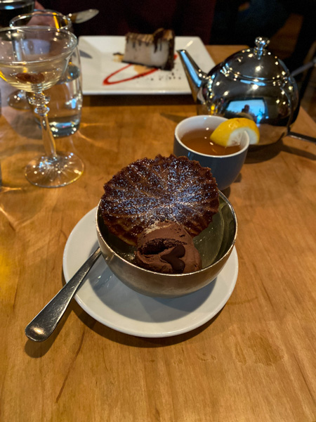 Plant Restaurant North Asheville Vegan Dessert with brown chocolate cookie in bowl of lemon and pine nut vegan ice cream next to silver tea pot if cup of tea garnished with lemon