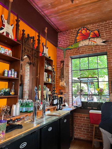 Asheville Guitar Bar in Asheville, North Carolina with wooden bar with liquor, wine, and beer taps next to open window with people sitting in front of it