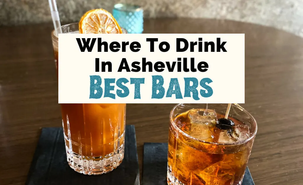 Best bars in Asheville NC with two brown cocktails on table, one in high ball glass with straw and lemon garnish and the other in a low ball with ice cubes and black cherry