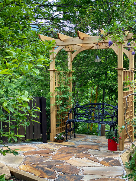 Flowering Garden Lake Lure NC with stone path leading to bench under trellis with purple flowers