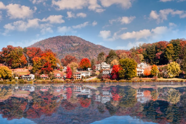 Junaluska Lake Near Asheville NC with fall foliage trees around lakeside homes with blue cloudy sky