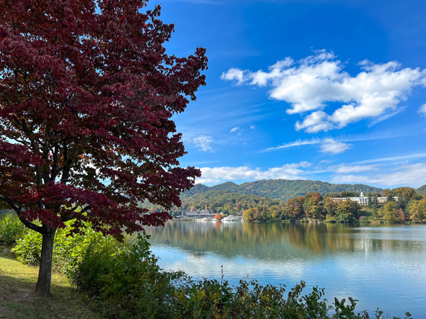 Lake Junaluska NC Fall Foliage with red tree, water, and lake surrounded by houses, hotel, and fall trees