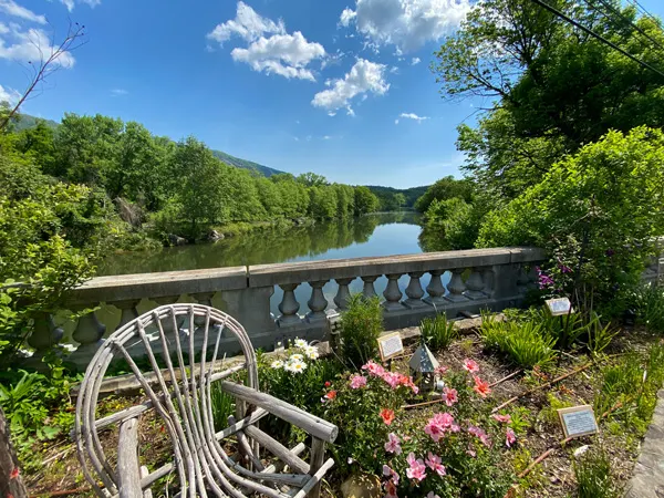 Lake Lure Flowering Bridge with flowers and wooden chair along bridge overlooking the water surrounded by green trees