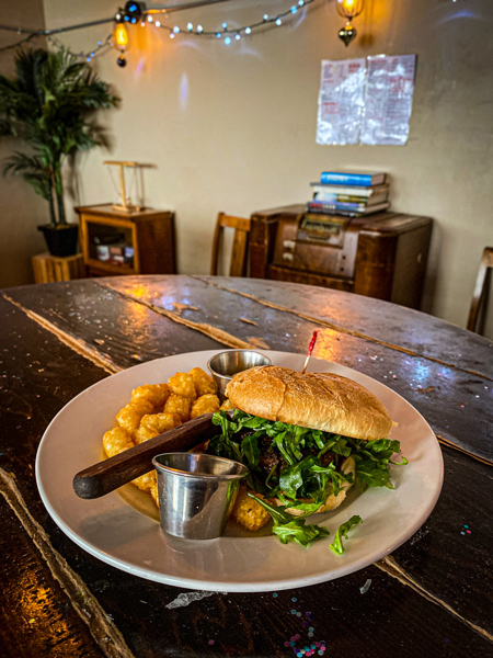 Rankin Vault Cocktail Lounge Asheville with burger with lettuce and bun on plate with tater tots