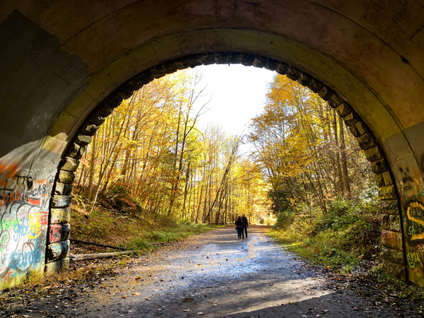 Road To Nowhere Bryson City with large tunnel with two people walking out of it into the yellow-green fall foliage