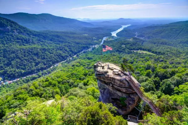 Chimney Rock Near Lake Lure NC with image of large rock formation jutting over mountains and green trees overlooking Lake Lure