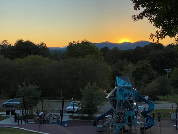 Hazel Robinson Amphitheatre Parking with sun setting over mountains and playground with cars parked around lots