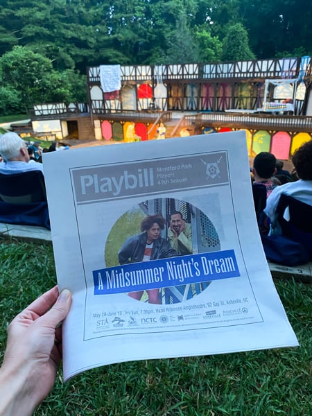 Montford Park Players Playbill with actors from a Midsummer's Night dream in front of stage with people sitting in lawn chairs around stage