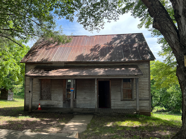 Henry River Mill Village NC Katniss Everdeen House with small two story wooden bare bones wooden home with trees and green grass