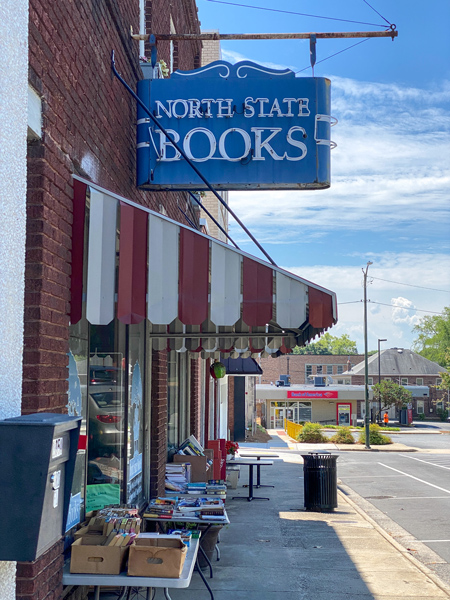 North State Books Lincolnton NC storefront with blue business sign over doorway and used books in boxes and on tables