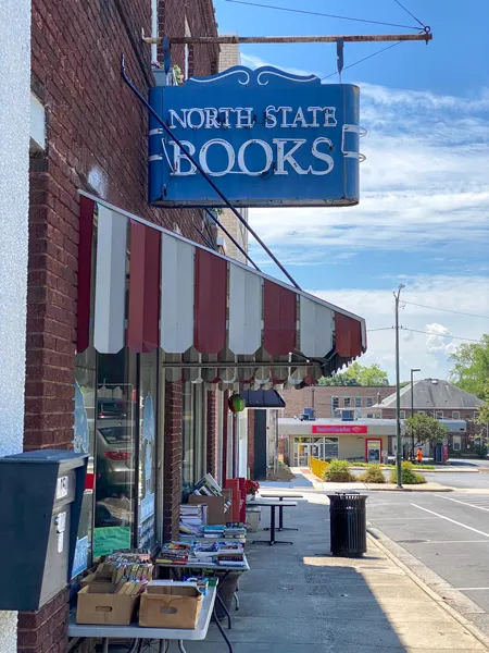 North State Books Lincolnton NC storefront with blue business sign over doorway and used books in boxes and on tables
