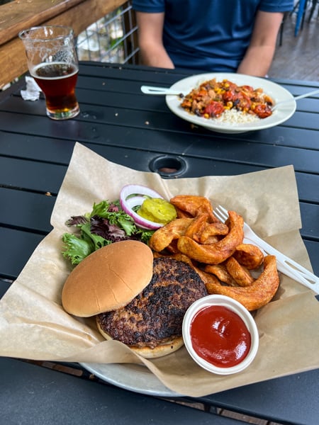 BearWaters Brewing Creekside Maggie Valley NC with burger on plate with fries, lettuce, pickles and onion and beer in background