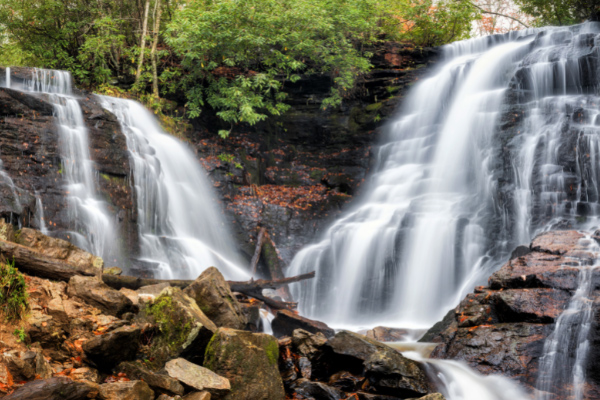 Soco Falls Maggie Valley NC which is double, side-by-side waterfalls with a rock base and trees in the background