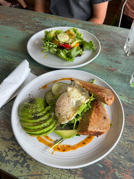 The Chef and The Baker Restaurant Maggie Valley NC with two white plates on table one with green salad and the other with avocado toast with an egg