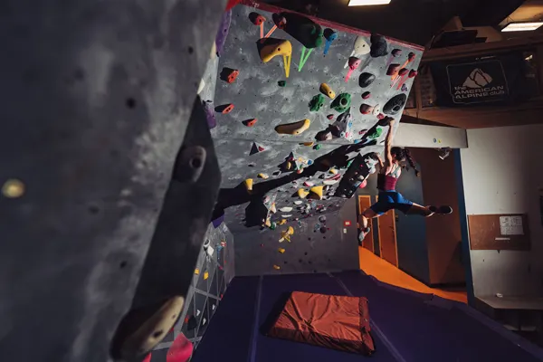 Cultivate Climbing Asheville NC with person with long braid holding onto rock wall boulder in a rock climbing gym