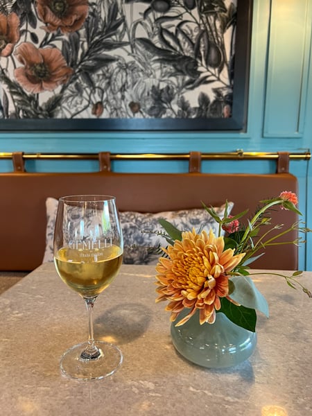 Gemelli Italian Eatery Asheville NC with white wine glass and turquoise vase of orange flowers on table