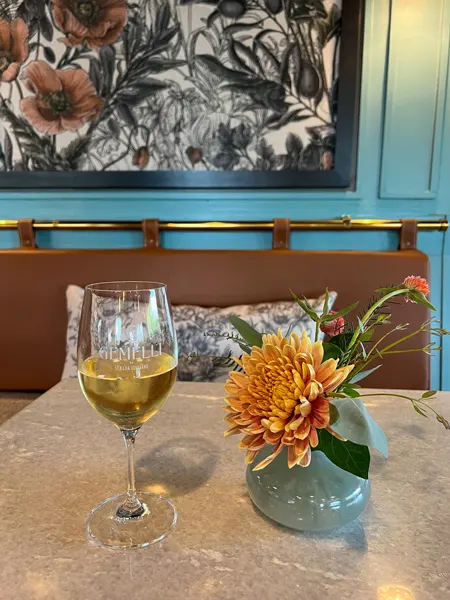 Gemelli Italian Eatery Asheville NC with white wine glass and turquoise vase of orange flowers on table
