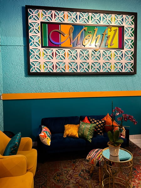 Mehfil Indian Restaurant Asheville North Carolina with colorful sign with name on blue and turquoise wall with blue couch and yellow chair
