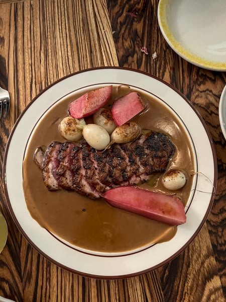 Plate of duck in gravy with red radishes on table at Neng Jr.'s Restaurant in Asheville NC