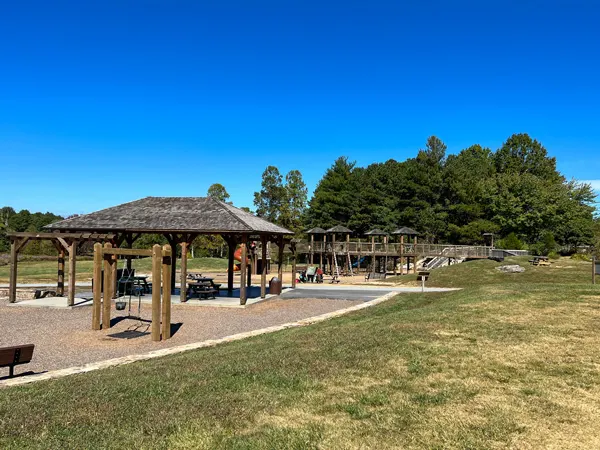 Park At Flat Rock North Carolina wooden playground and picnic pavilion with trees and bright blue sky