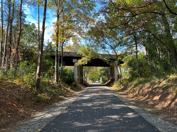 Thermal Belt Rail Trail Spindale to Forest City NC with paved and flat trail going under bridge surrounded by trees