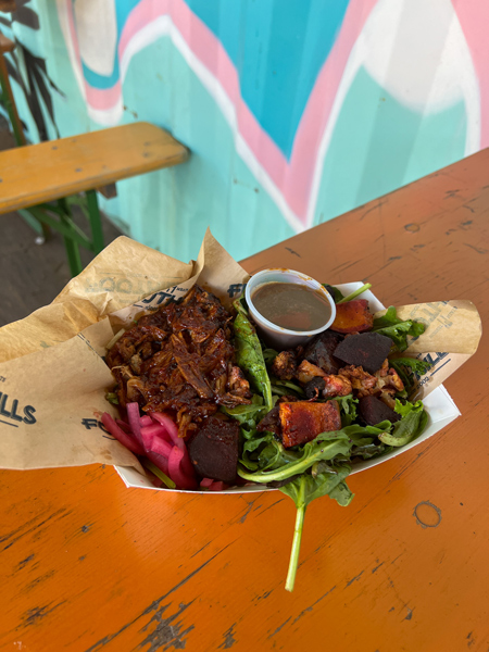 Foothills Food Truck At Hi Wire Beer Garden Asheville NC with image of pulled pork BBQ on salad in throw-away bowl on table with mural in background