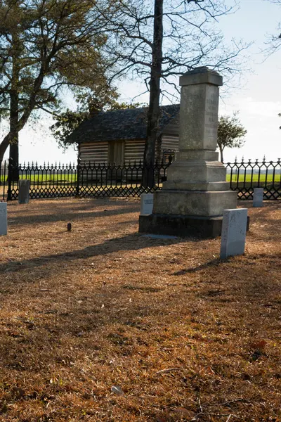 Chicora Civil War Cemetery at Averasboro Battlefield and Museum in North Carolina with image of Confederate monument, small house like structure, and tombstone with tree