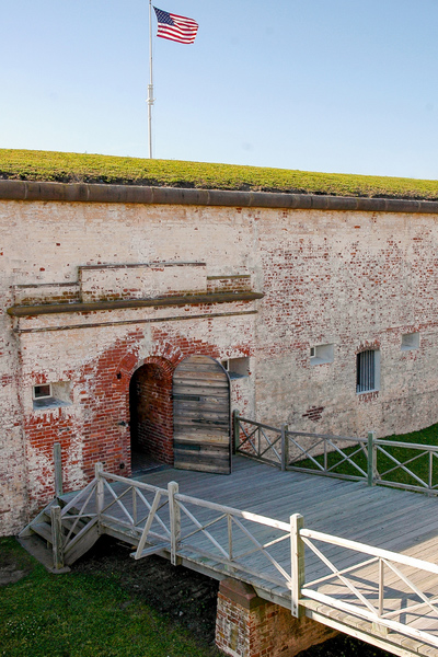 Fort Macon State Park with image of wall of fort with bridge leading to arch doorway and American flag on top