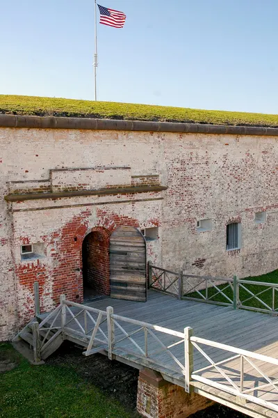 Fort Macon State Park with image of wall of fort with bridge leading to arch doorway and American flag on top